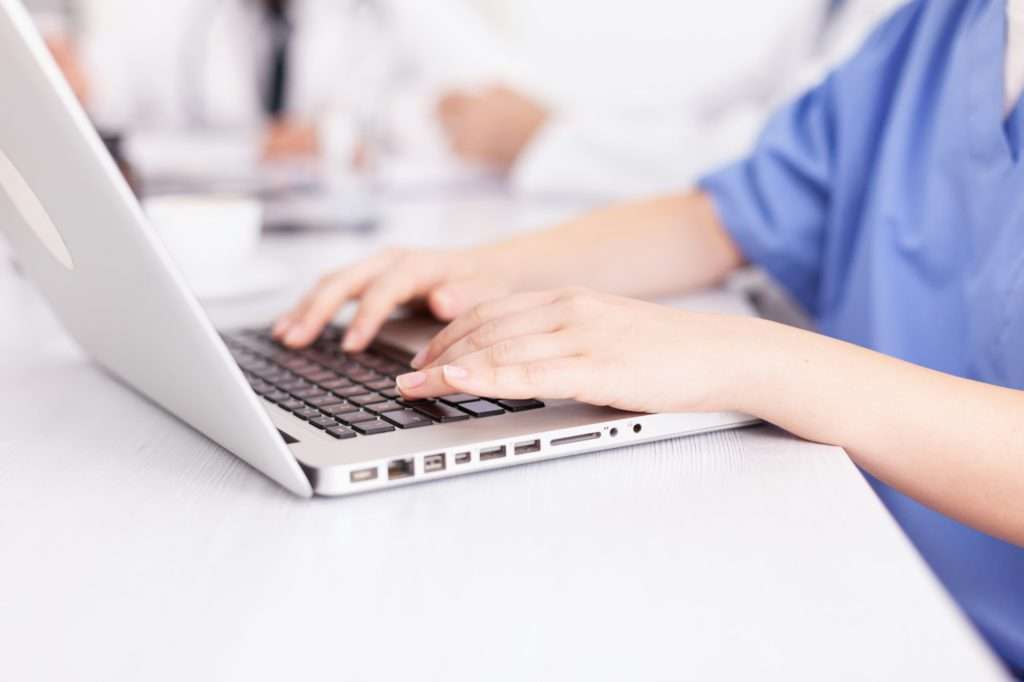 Close up of medical nurse typing on laptop